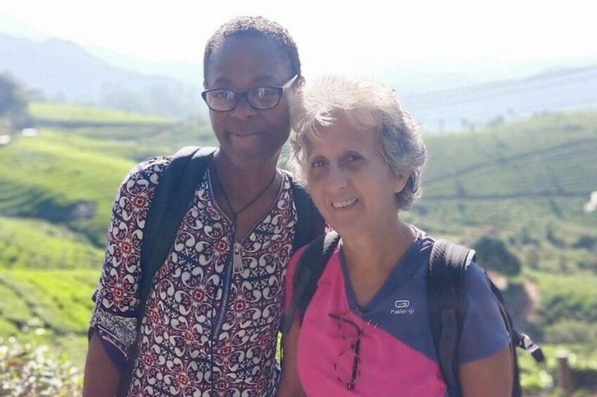 Two people standing on a hill with a mountainous landscape in the background. 5