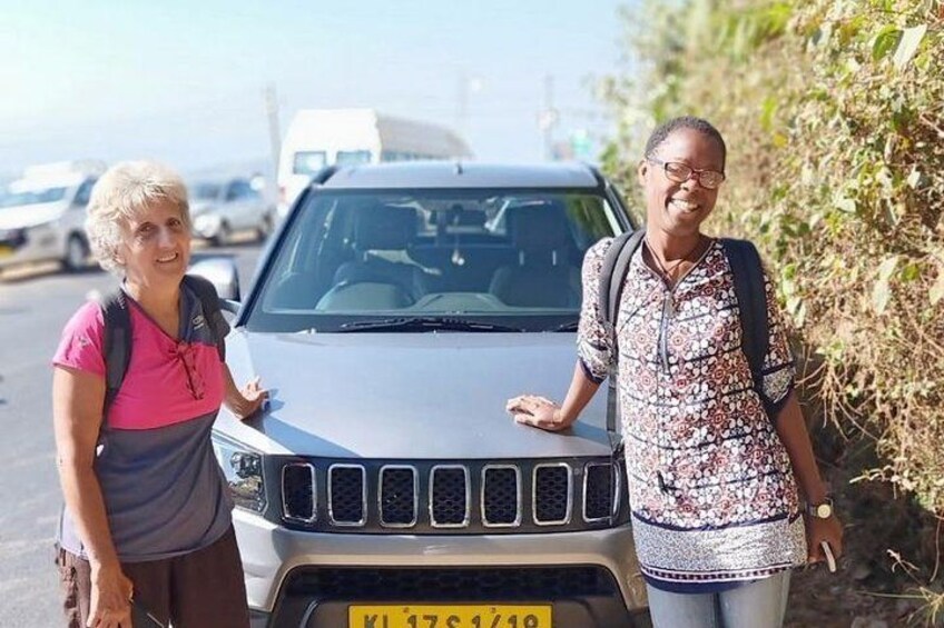 Two people standing beside a vehicle with a visible license plate. 2