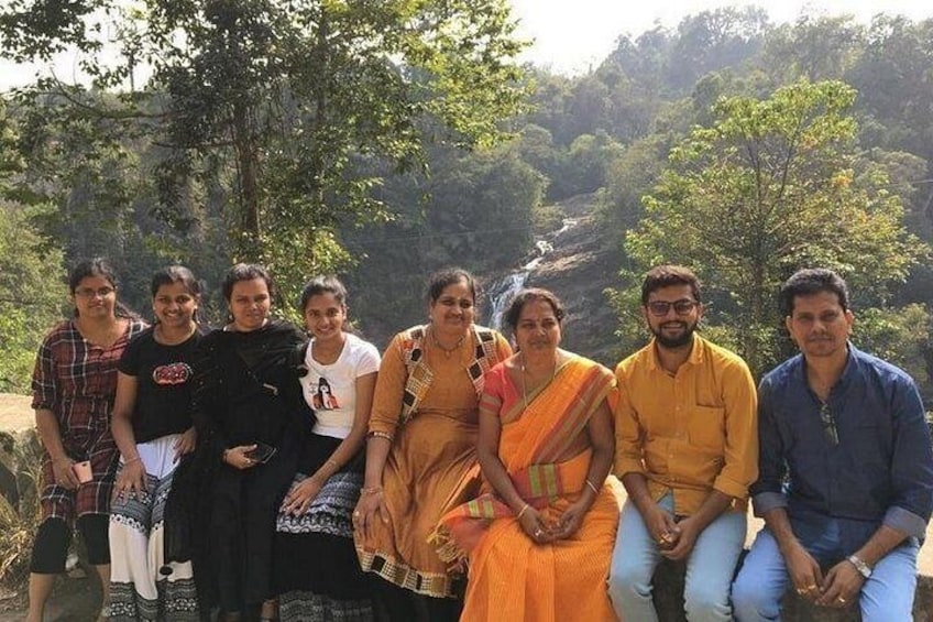 A group of people outdoors, some in traditional attire, with a mountainous landscape in the background. 2