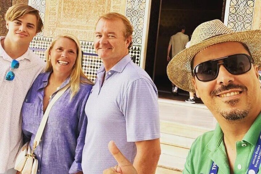A group of people standing in front of a building with intricate tile work. 1