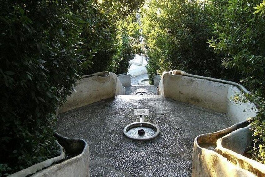 A pathway with a central drainage grate surrounded by concrete planters. 5