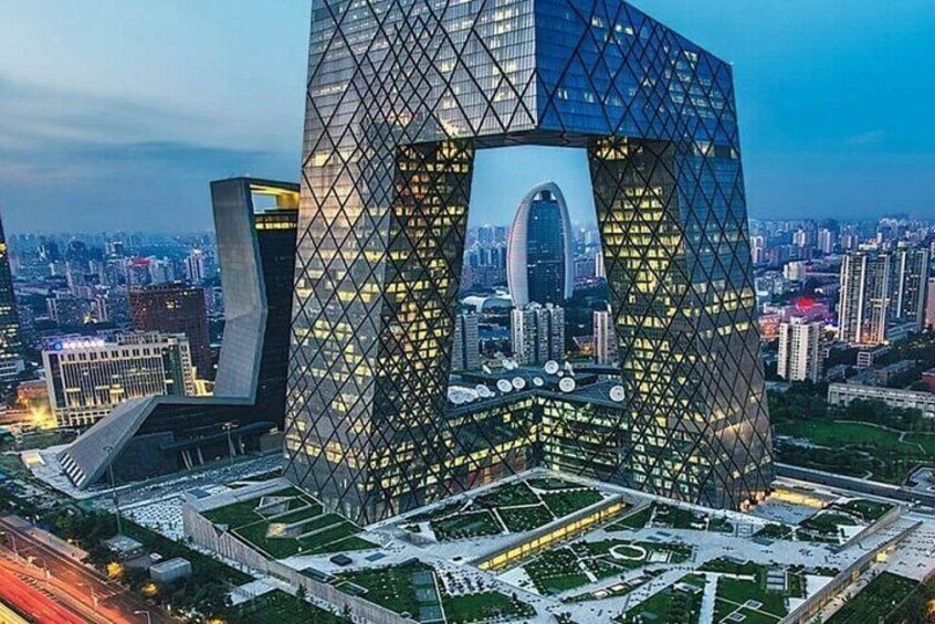 A modern architectural structure with a distinctive geometric design, surrounded by a landscaped area and urban skyline. 5