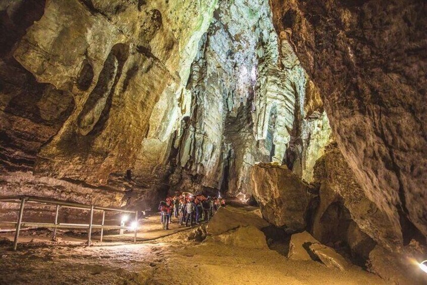 A cave with stalactites and stalagmites, a group of people, and a metal railing. 3