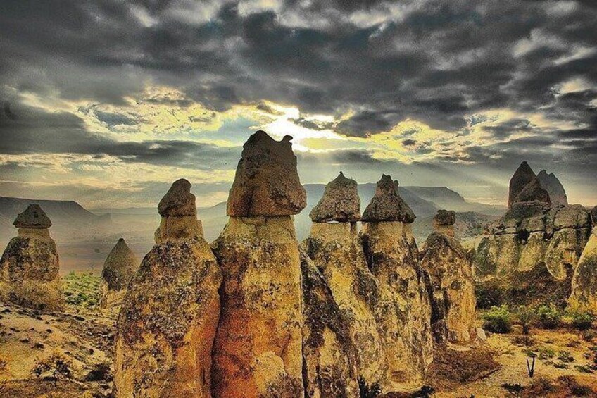 Un paesaggio con formazioni rocciose particolari, un cielo nuvoloso e montagne in lontananza. 2