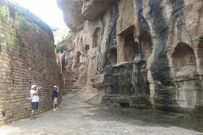 A narrow canyon with ancient rock carvings and a brick wall. 3