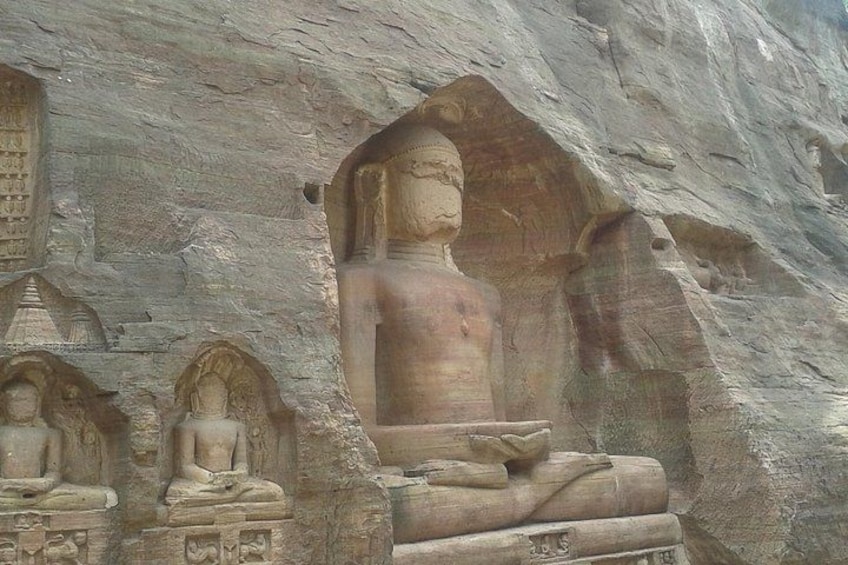 A large Buddha statue carved into a cliff face, surrounded by smaller statues and intricate carvings. 5