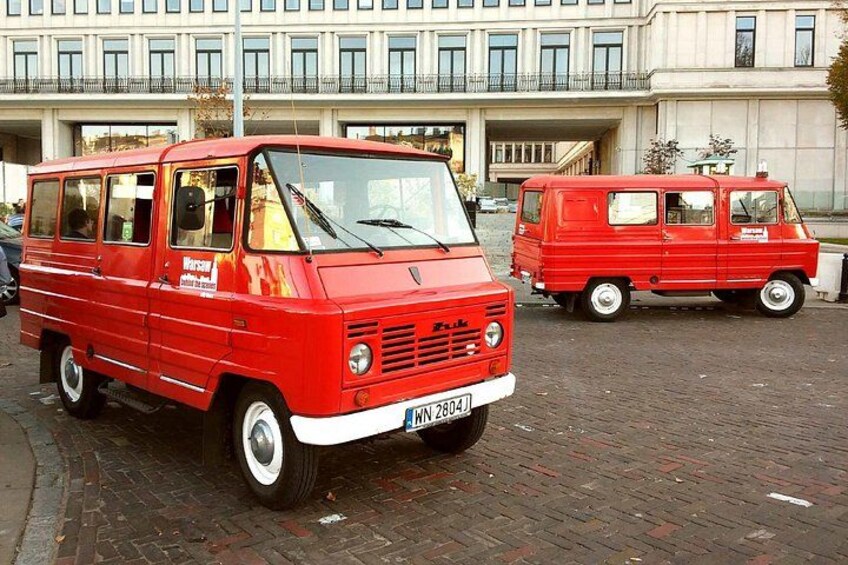 A red van parked on a cobblestone street with a building in the background. 4