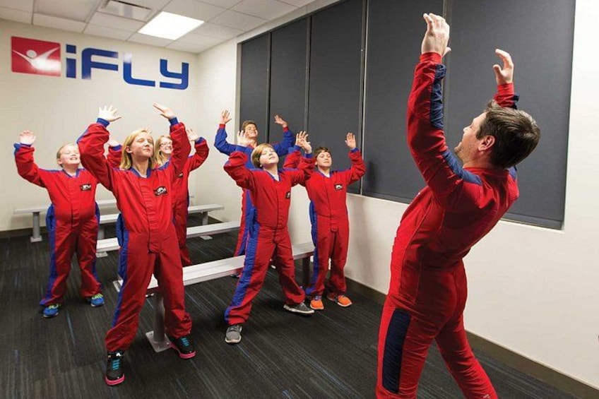 Un groupe de personnes vêtues de costumes rouges et bleus effectue un exercice dans une pièce dotée d’un grand miroir et d’un logo sur le mur. 4