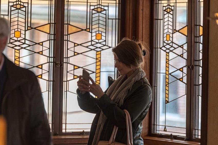A person using a smartphone indoors near a window with stained glass. 3