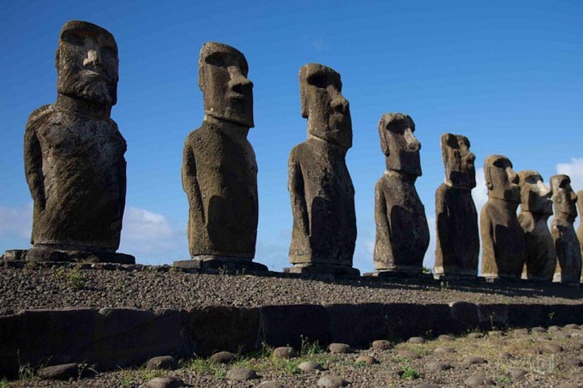Une rangée de grandes statues de pierre, vraisemblablement les Moaï de l’île de Pâques, sous un ciel dégagé. 1