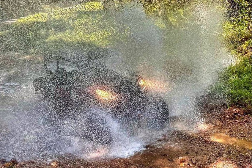 A person riding a motorcycle through a splash of water, likely from a puddle or stream. 5