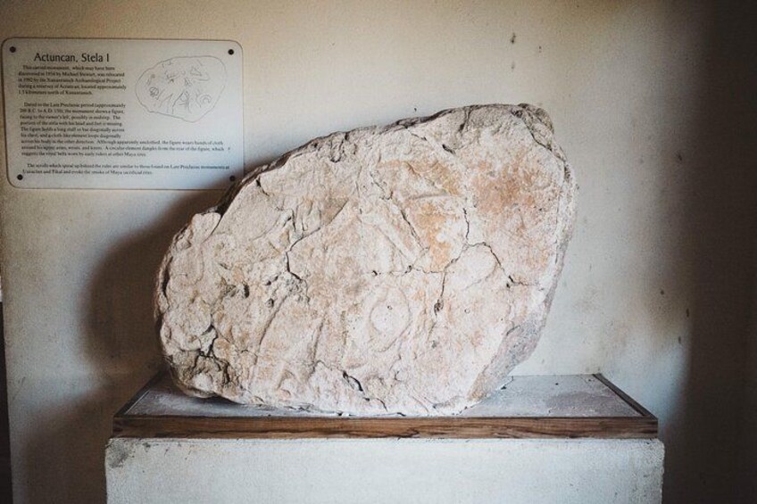 A large, rough-textured stone slab with visible cracks and a label in the background. 3