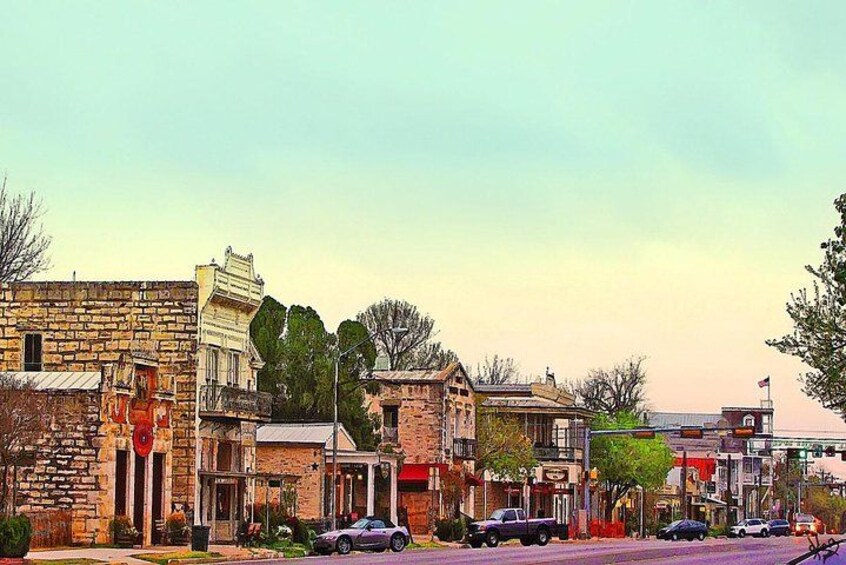 A street lined with historic buildings, parked cars, and a clear sky. 1