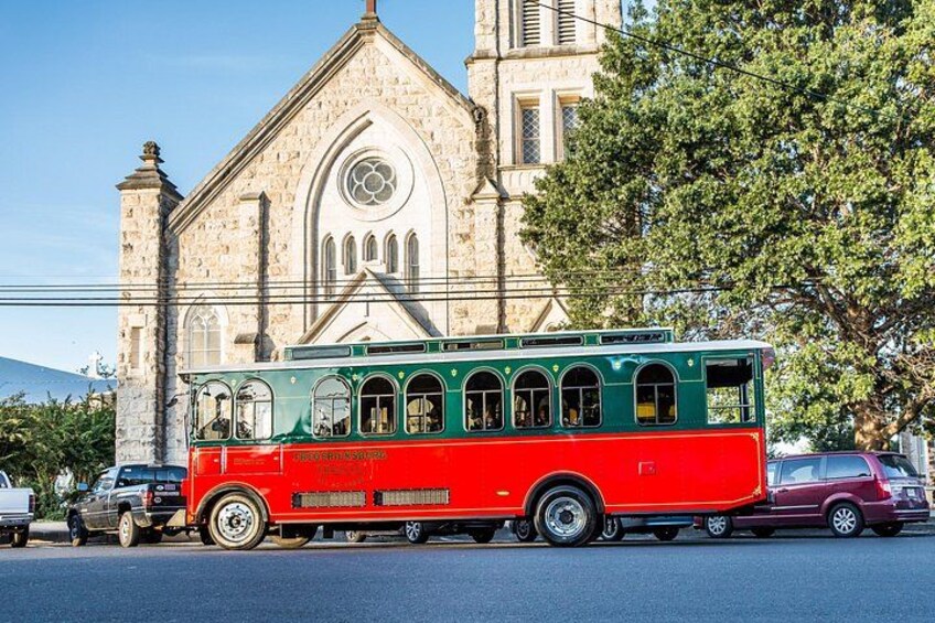 A red and green bus parked on a street with a church in the background. 3