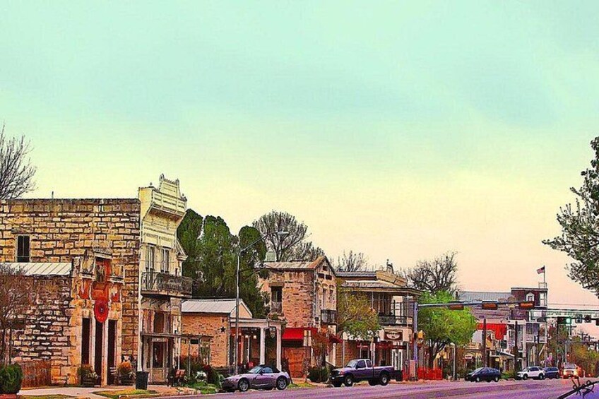 A street lined with historic buildings, a stop sign, and parked cars. 1