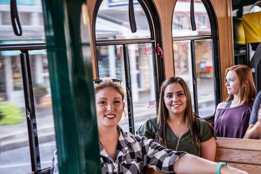 A bus interior with large windows, a wooden table, and a person leaning out of the window. 2