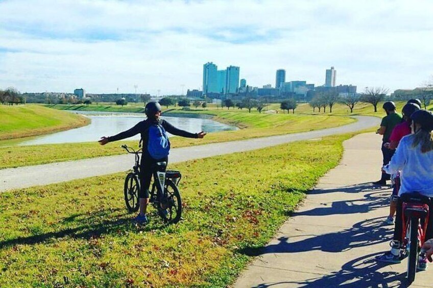 A person on a bicycle on a path with a city skyline in the background. 5