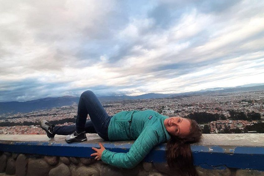 A person lying on a ledge with a cityscape in the background. 1