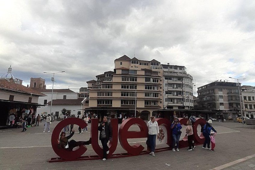 A public square with a large red sculpture spelling 'LOVE' and people around it. 4