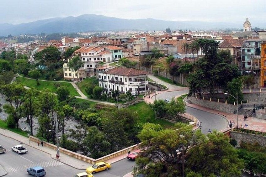 A cityscape with a winding road, historic buildings, and a distant mountain range. 5