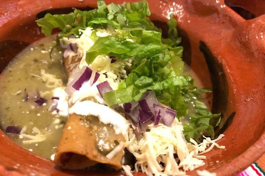Un pot en argile traditionnel rempli d’une sauce verte, garni de fromage râpé, de laitue et d’oignon rouge. 3