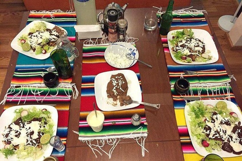 Une table dressée avec des nappes aux couleurs vives, des assiettes remplies de nourriture et divers condiments. 4