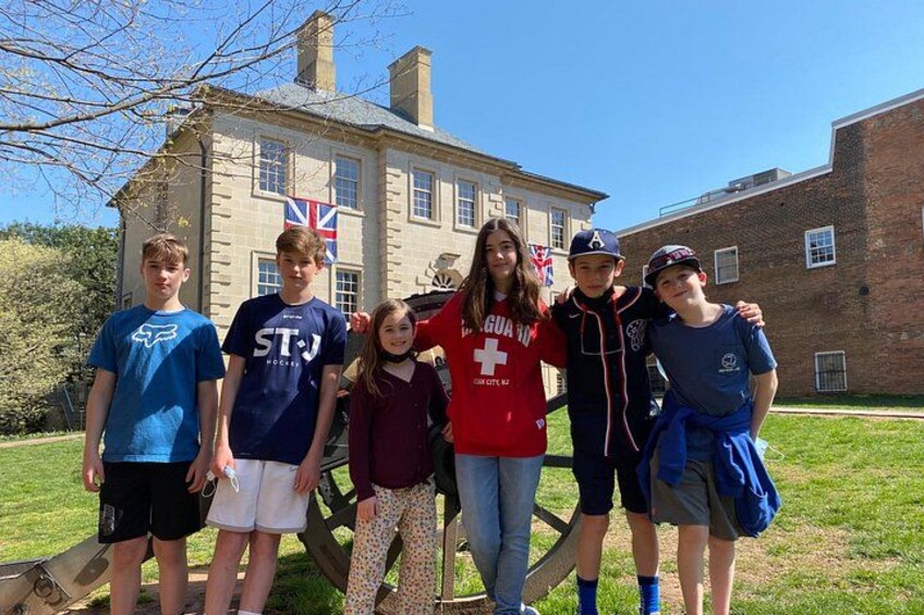 A group of people standing in front of a building with a Union Jack flag. 2