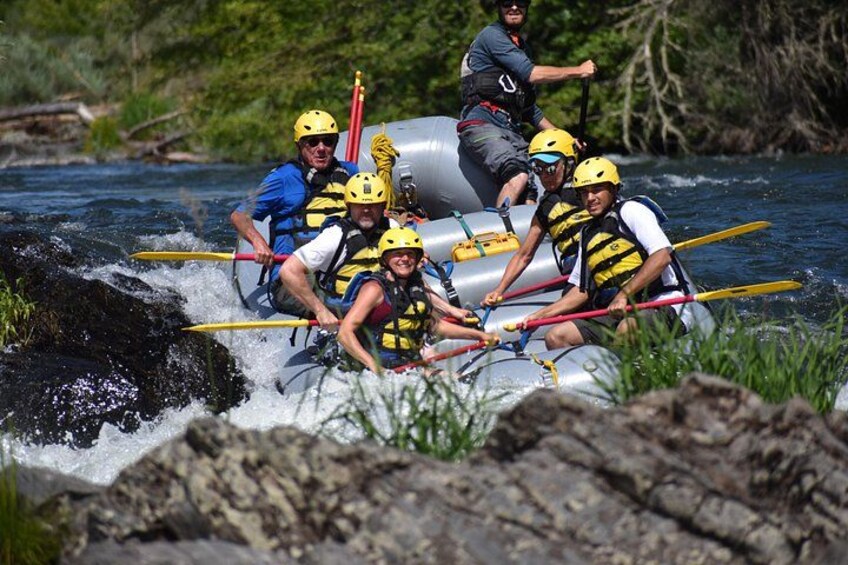 A group of people rafting on a river with rocks and greenery in the background. 3