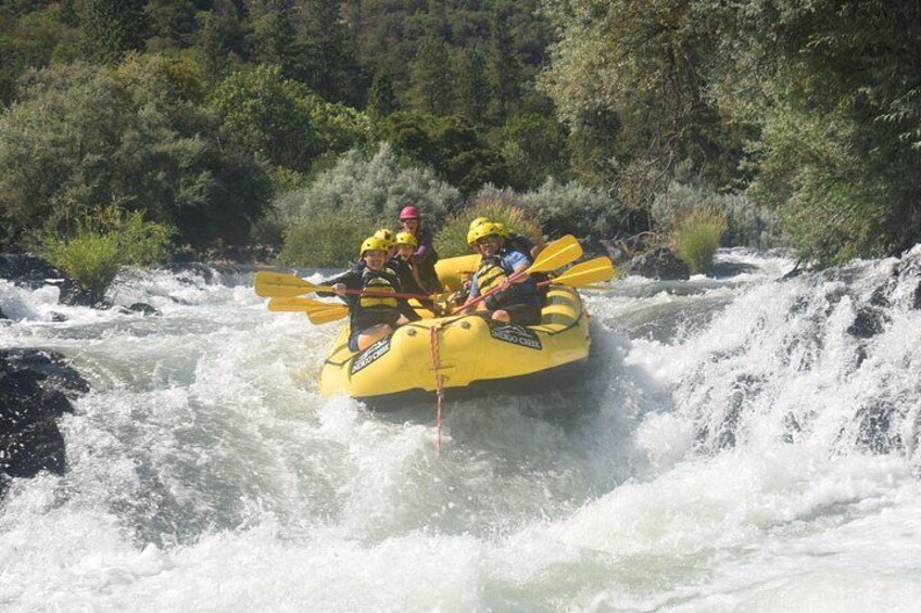 Two people in a yellow raft navigating a river with rapids. 4