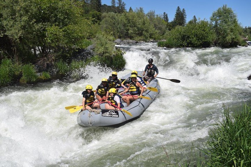 A group of people in a raft navigating a river with rapids. 2