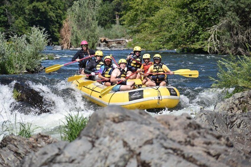 A group of people in a yellow raft navigating a river with rapids. 5