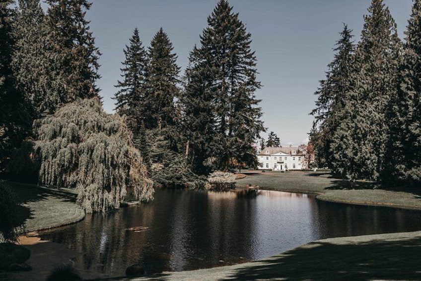 Un lac entouré de grands arbres, un bâtiment en arrière-plan et un ciel dégagé. 1