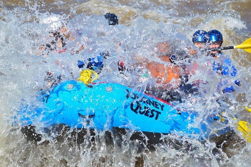 A white water rafting activity with participants in blue and orange rafts. 2