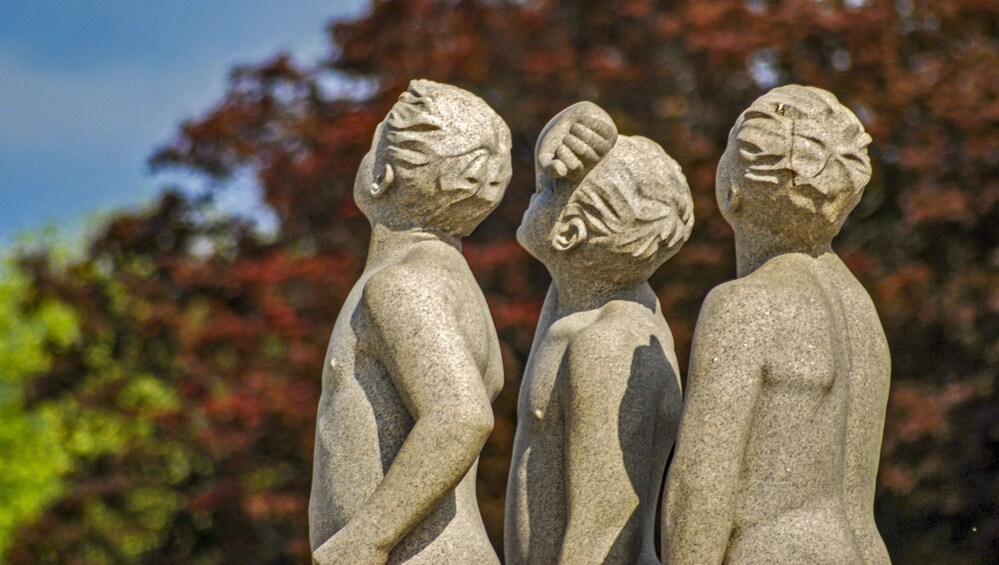 Three stone sculptures of human figures in a garden. 5