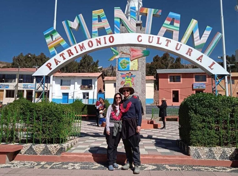 Un senyal amb la inscripció "AMANTANI PATRIMONIO CULTURAL", un arc de colors i un mapa al fons. 3