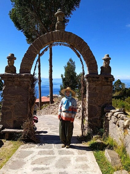Una persona al peu d'una antiga arcada de pedra amb una vista del mar al fons. 5