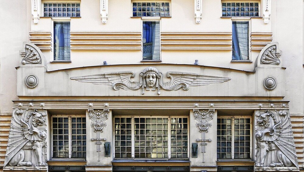A building facade with ornate sculptures, large windows, and decorative elements. 2