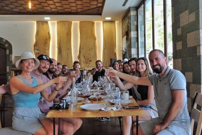 A group of people toasting at a long dining table in a restaurant with a rustic interior. 3