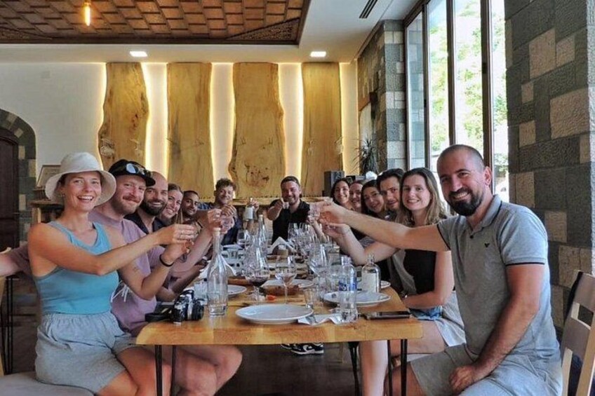 A group of people seated around a table in a restaurant with a wooden interior and large windows. 3