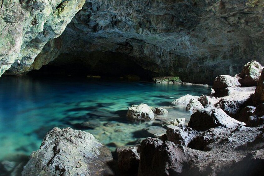 Una cueva con agua azul cristalina y grandes rocas. 1