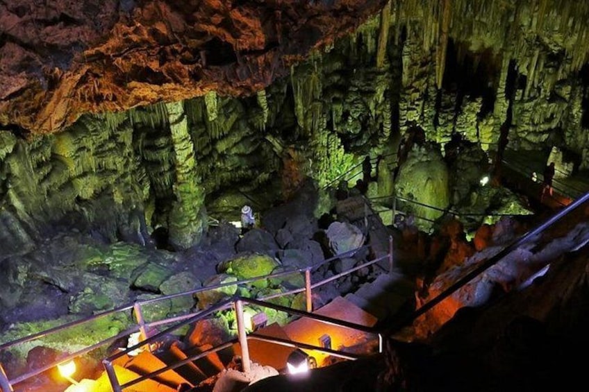 Una cueva con estalactitas, un pasillo metálico y una persona escalando. 2
