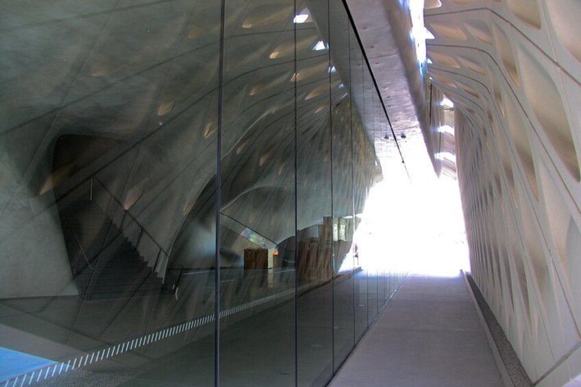 Una estructura arquitectónica moderna con superficies reflectantes y un pasillo de cristal. 3
