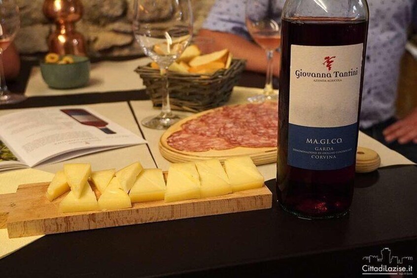 A table with a bottle of Giovanni Tanini Magloco Garde, cheese, and cured meats. 2