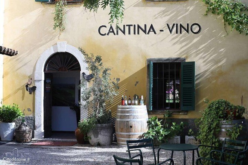 A building named 'CANTINA - VINO' with outdoor seating and potted plants. 5
