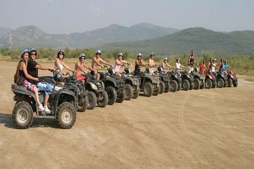 Un groupe de personnes conduisant des quads sur un chemin de terre, avec des montagnes en arrière-plan. 4