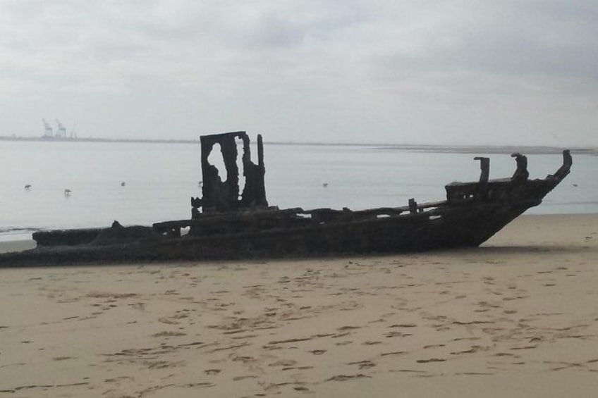 A sunken shipwreck on a sandy beach with a calm sea in the background. 5