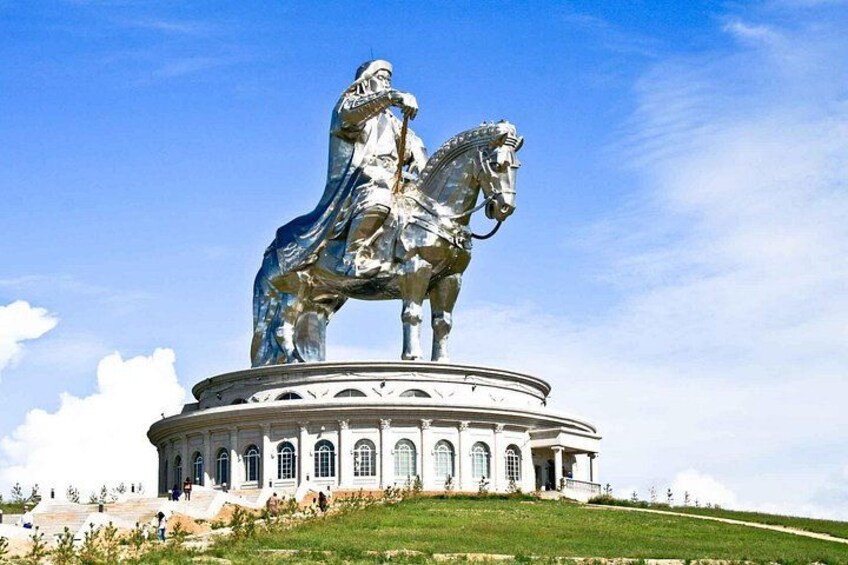 A large equestrian statue on a circular pedestal with classical architecture, set against a clear sky. 2