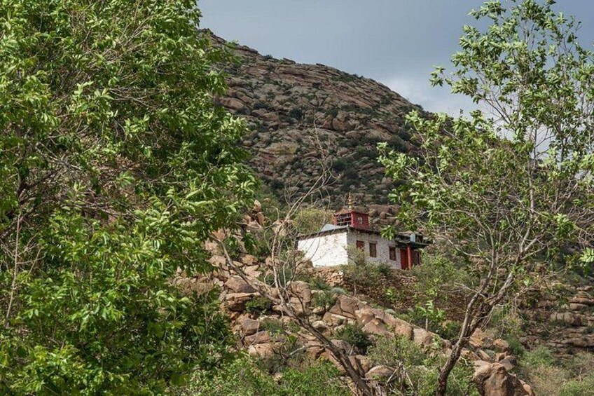 A small building with a red roof, surrounded by rocky terrain and green foliage. 4