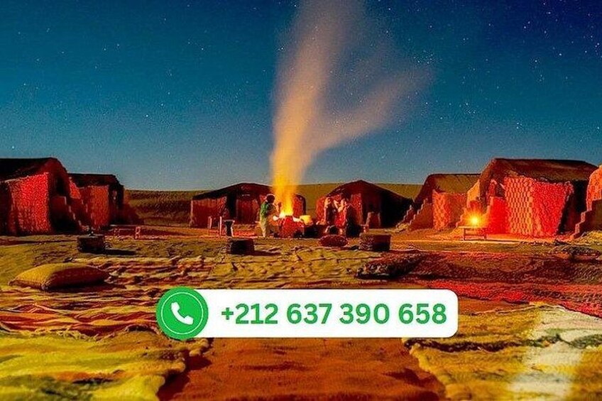 A rural landscape with red-roofed buildings, a campfire, and a clear night sky. 1