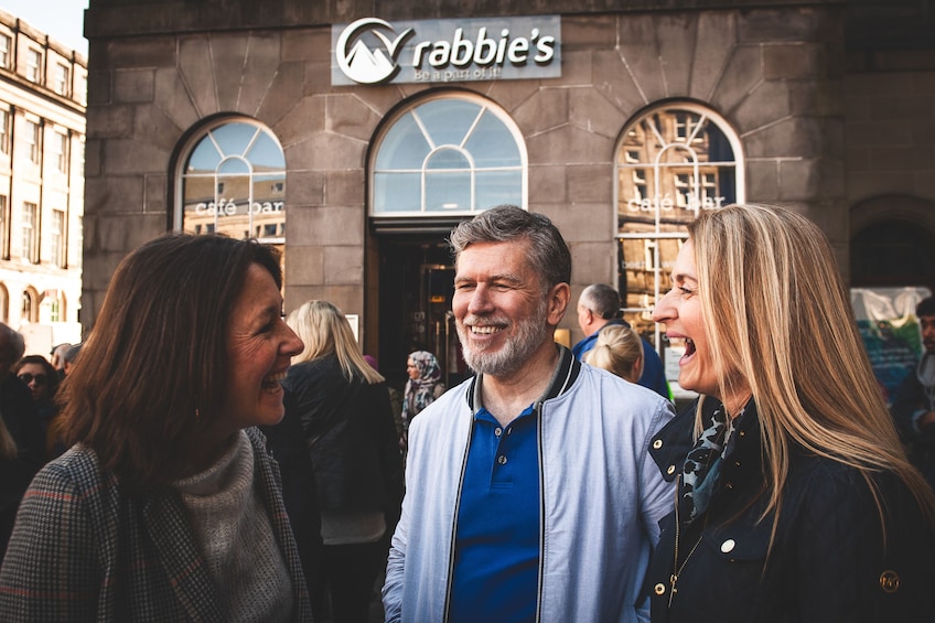Three people standing in front of a building with a sign that reads "Rabbie's". 5